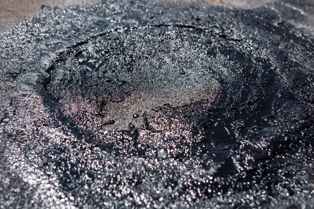 Crater-like damage from hail, causing gravel/granules to move around