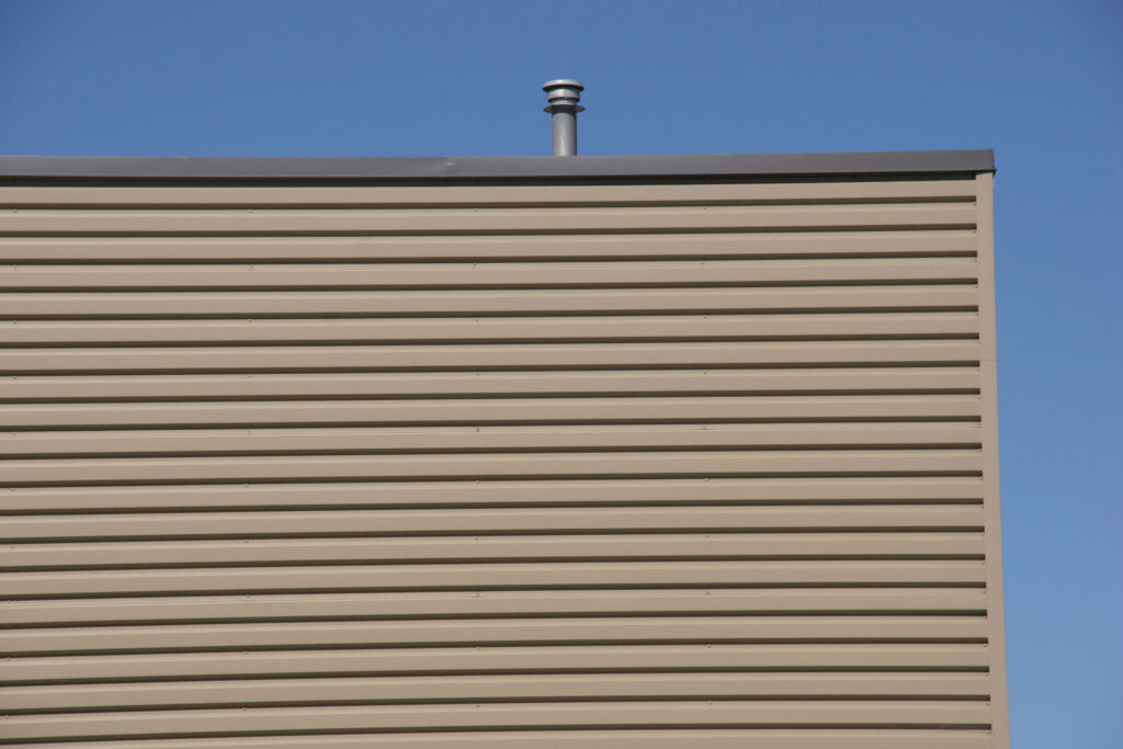 The side of a commercial building. There is a brown piece of metal running against the side of the building near the roof. This is the flashing.