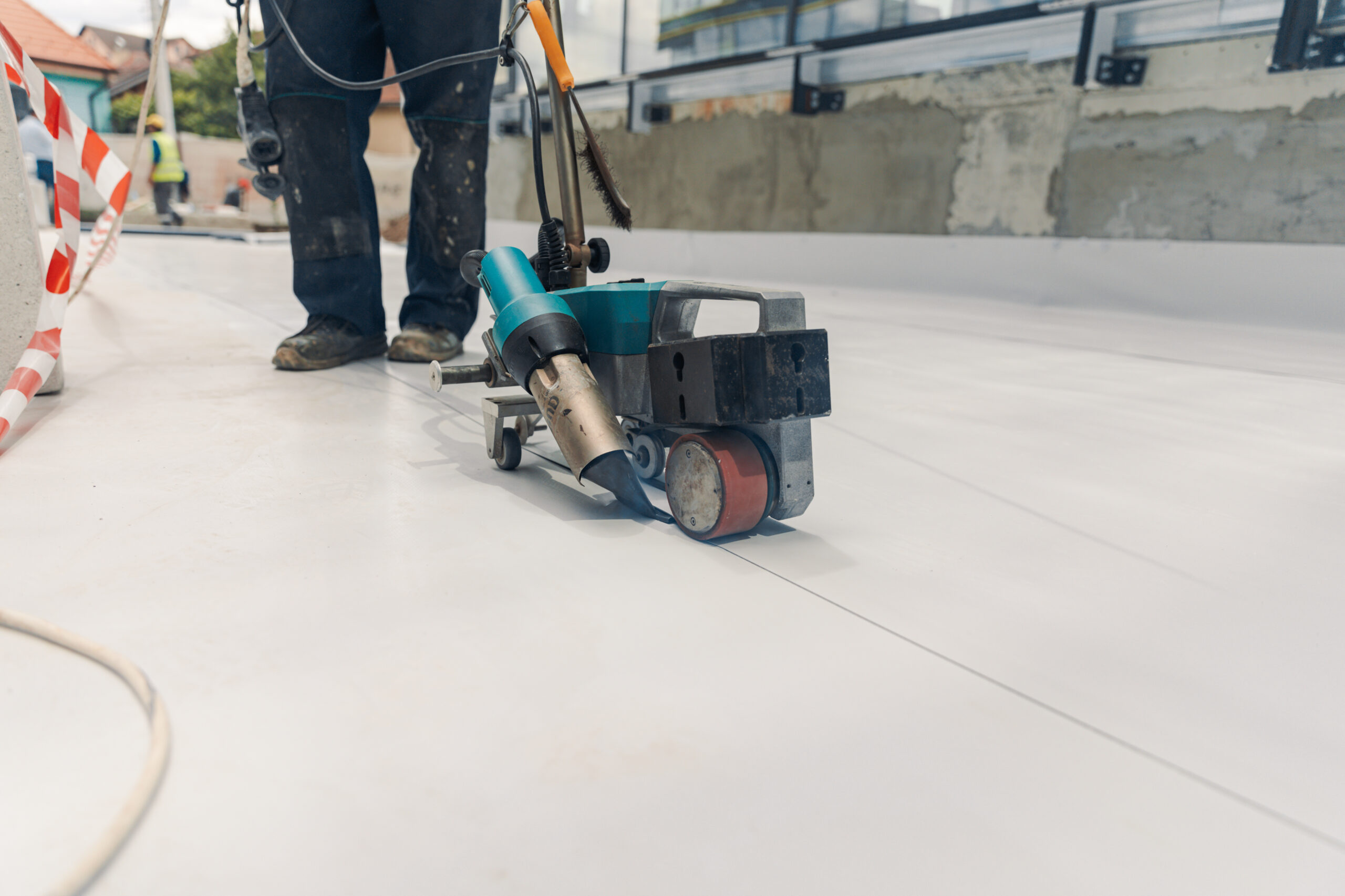 Worker welding white TPO roofing membrane 