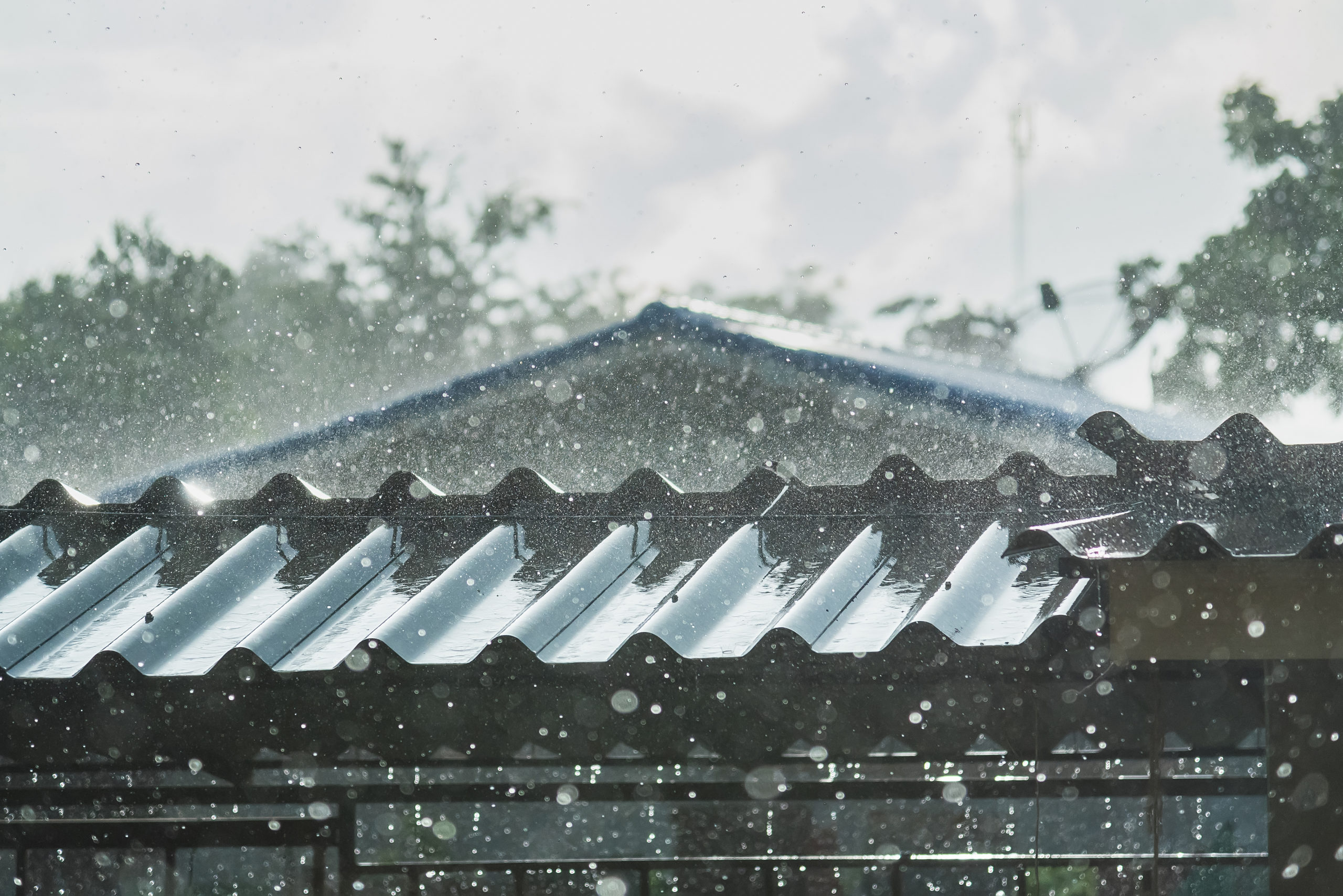 Close-up photo a metal roof being rained on in the middle of a storm