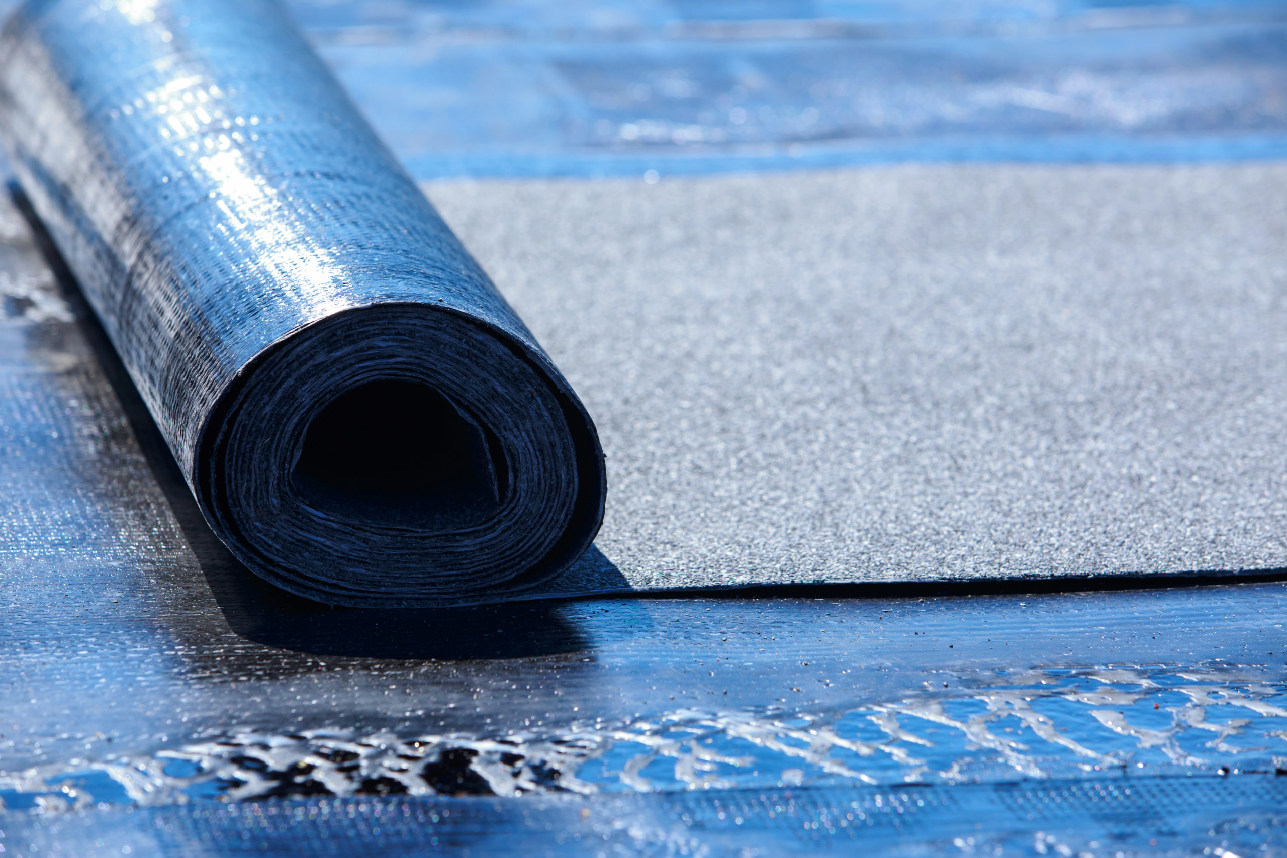 rubber roofing being unrolled on top of a roof