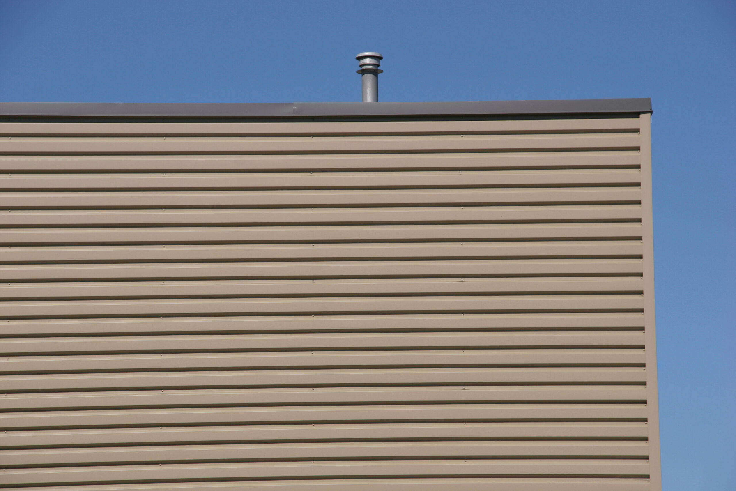 The side of a commercial building. There is a brown piece of metal running against the side of the building near the roof. This is the flashing.