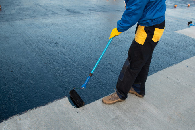 Rubber being applied to a commercial roof by a worker