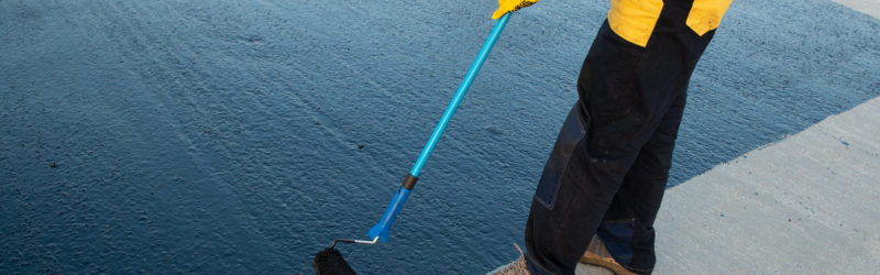 Rubber being applied to a commercial roof by a worker