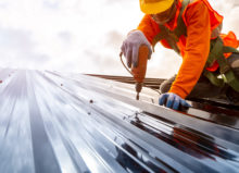 construction worker using electric drill to install a commercial steel roof
