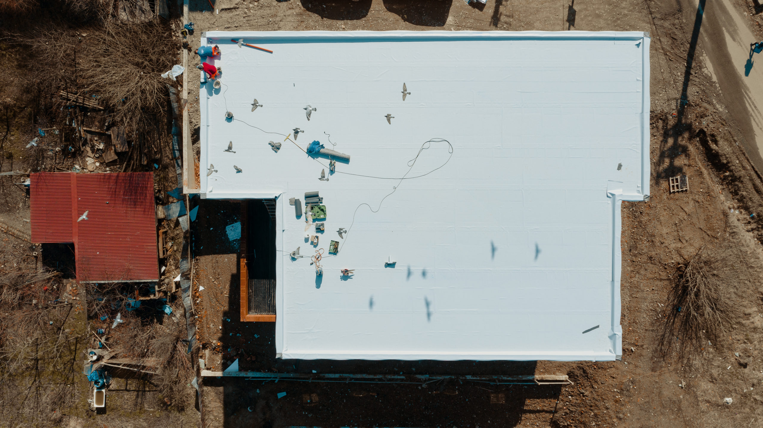Aerial view of an apartment building with flat roof in construction, ballasted system with EPDM membrane