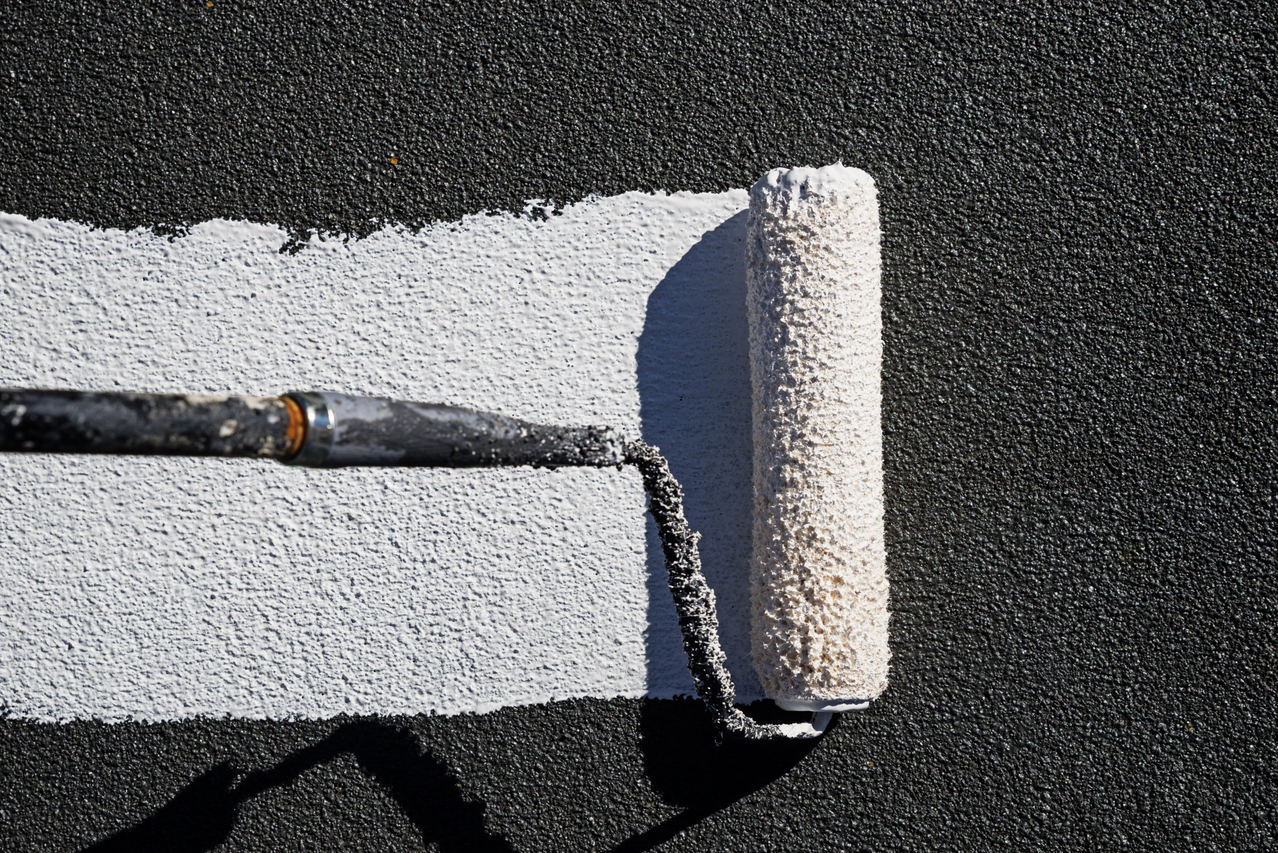 painting a roof with reflective white elastomeric coating with a paint roller