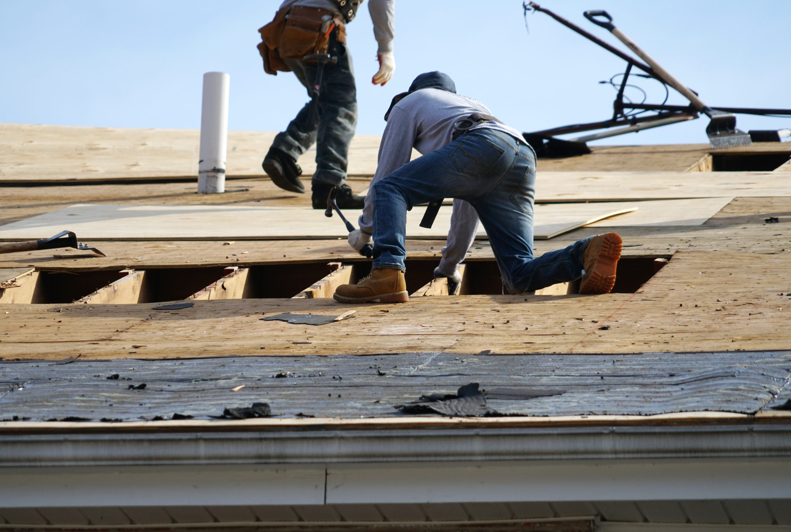 two construction workers doing work on an unfinished flat roof