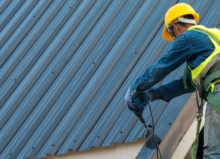 Construction worker wearing safety harness while working on roof structure