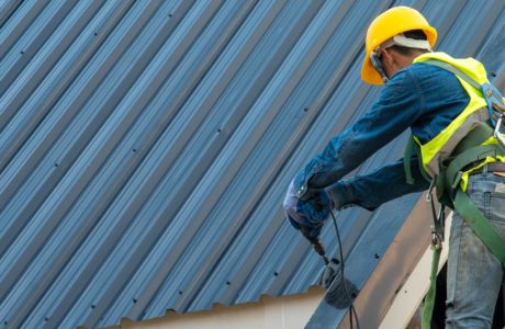 Construction worker wearing safety harness while working on roof structure