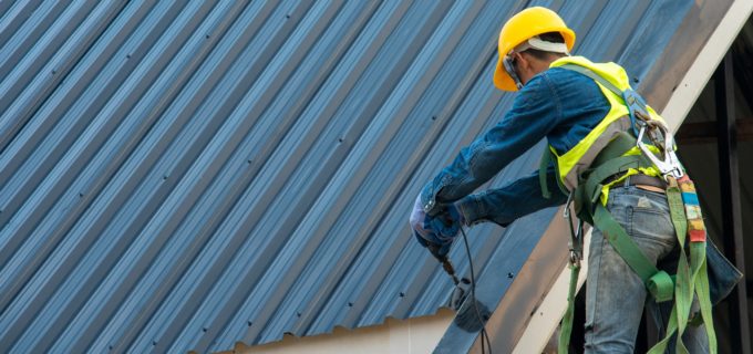 Construction worker wearing safety harness while working on roof structure