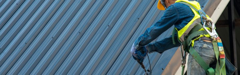 Construction worker wearing safety harness while working on roof structure