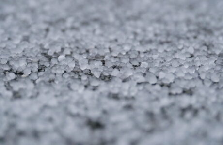 Small hail accumulated on the ground. The hail is covering the ground so much that you can barely see the asphalt.