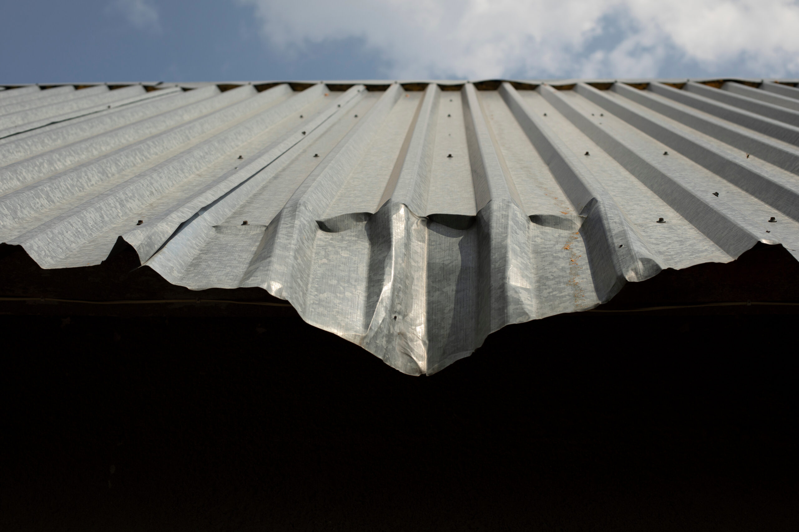 A sloped metal roof is dented at the bottom, indicating damage
