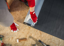 A roofer installs EPDM roofing on a plywood roof